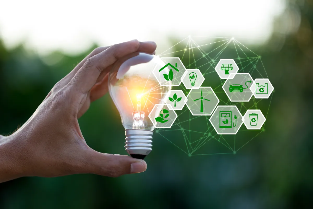 Hand holding a light bulb surrounded by green energy icons