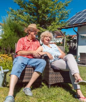 Couple relaxing in a garden beside a solar powered home
